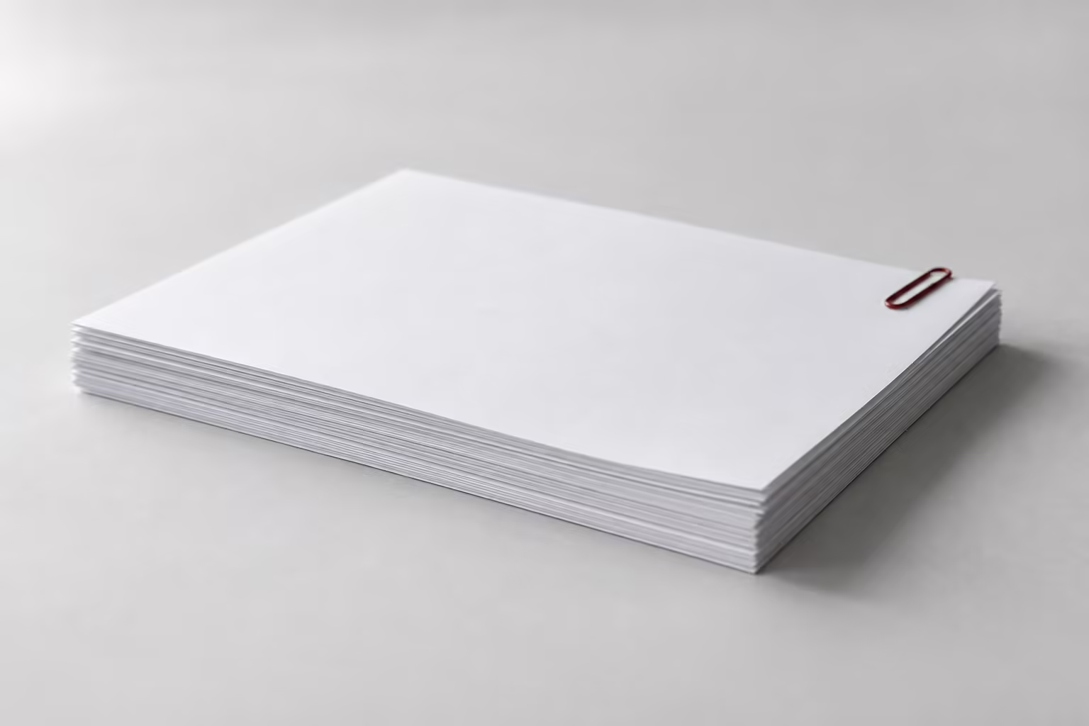 A short stack of white paper on a grey surface